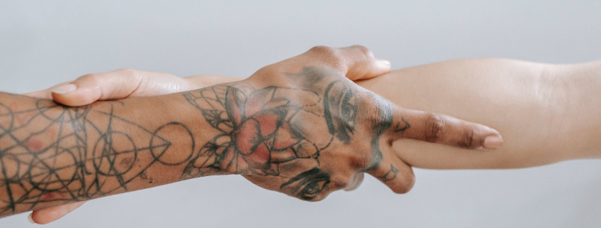 Two hands holding one another - one with tattoos.